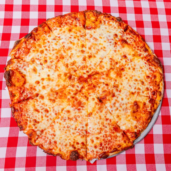 A whole cheese pizza, cut into slices, on a red and white checkered tablecloth.